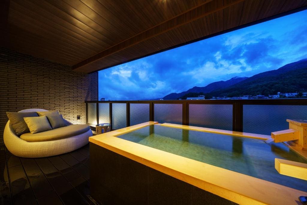 Private open-air bath with a mountain view and lounge seating on the balcony at Aburaya Tousen