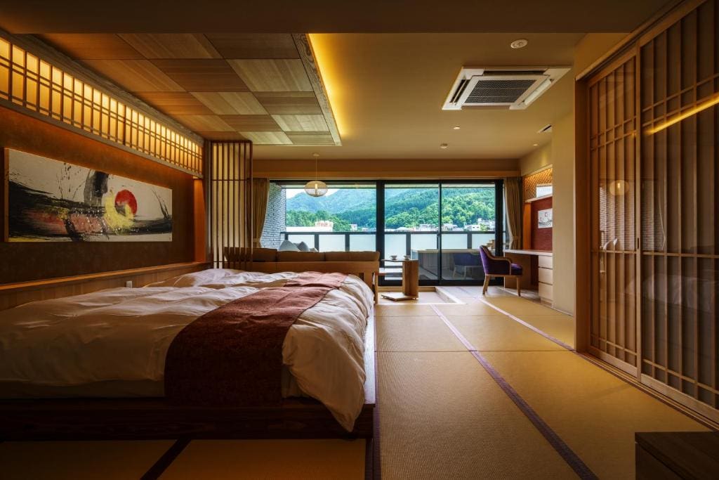 Spacious tatami room with twin beds, a large window, and mountain view at Aburaya Tousen