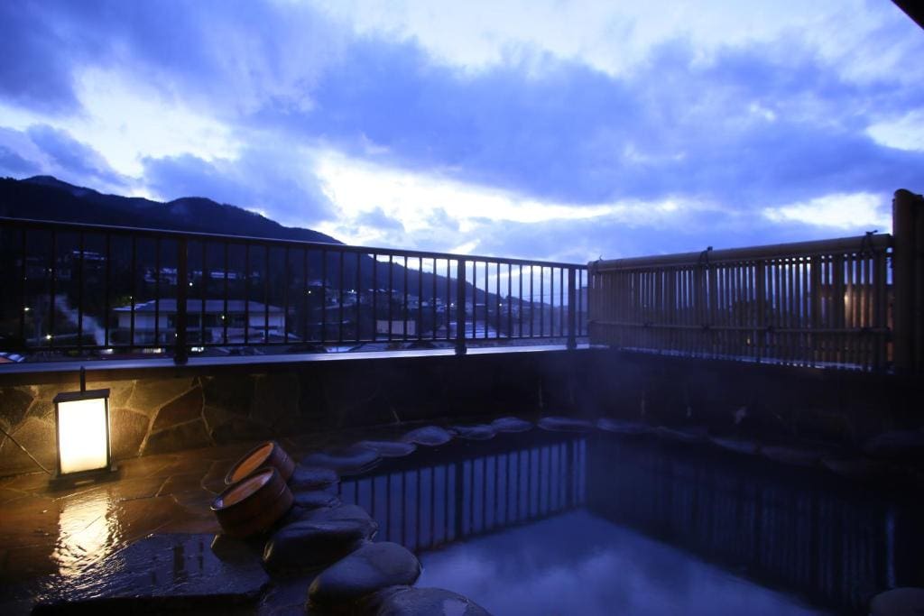 Open-air onsen bath with stone surround and mountain view at Ichinoyu Katei