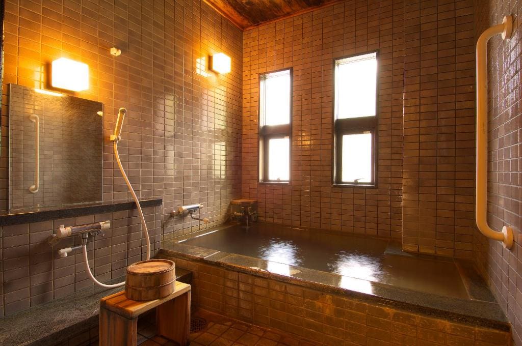 Indoor private bath with tiled walls and hand shower at Ichinoyu Katei