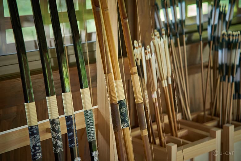 Traditional Japanese bows and arrows neatly displayed in a wooden rack, showcasing the intricate craftsmanship of archery equipment used in yabusame