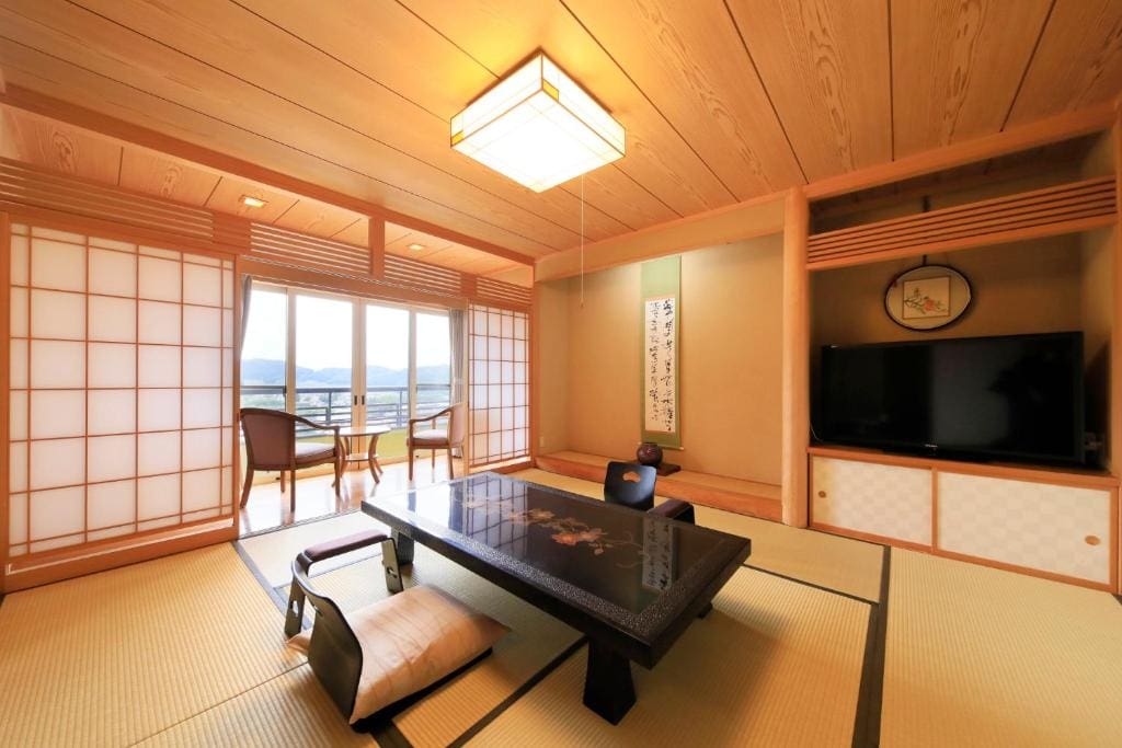 Tatami room with low table, chairs, and mountain view at Ryokan Biyu no Yado