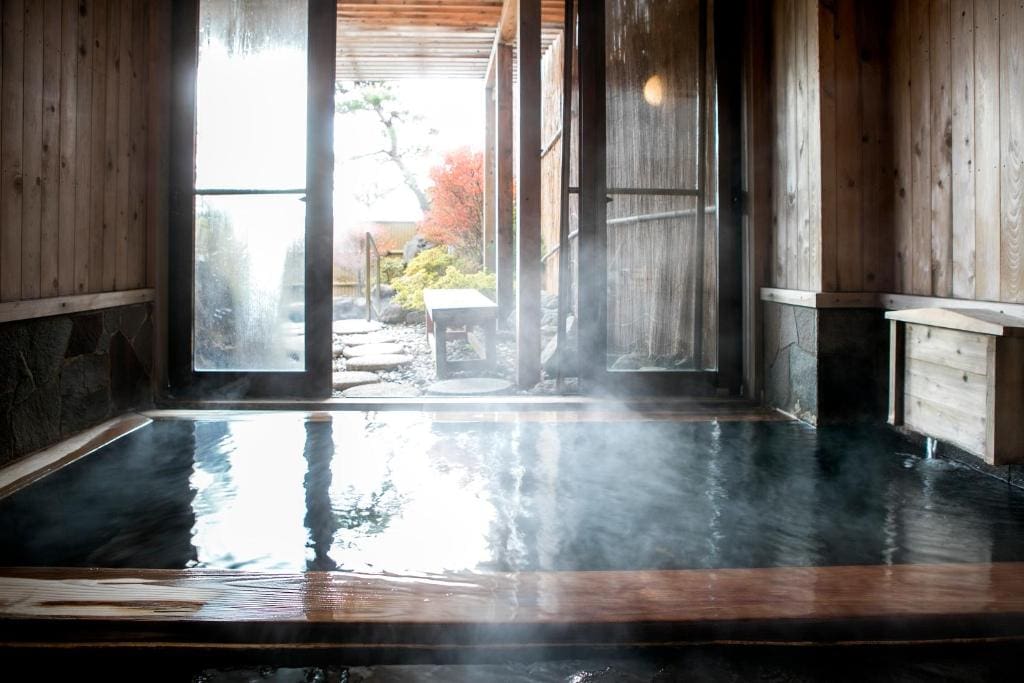 Private onsen bath with wooden interior and garden view at Ryokan Warabino