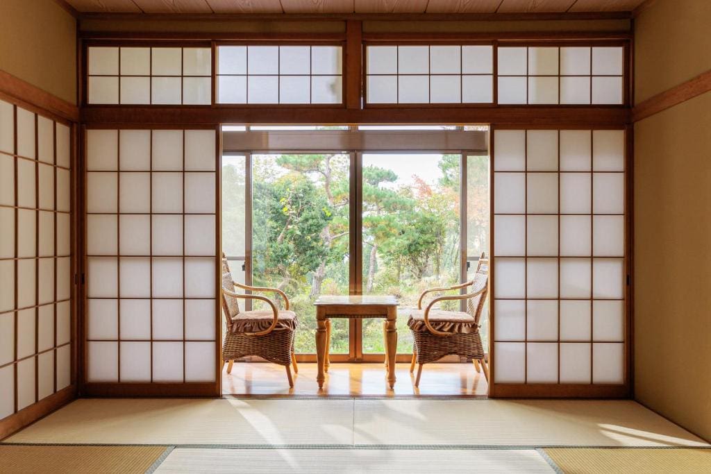 Tatami room with shoji screens and seating area facing a garden at Ryokan Warabino