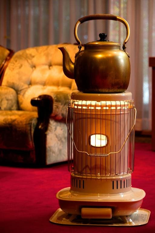 Vintage-style kettle placed on a kerosene heater in the lounge at Ryokan Warabino