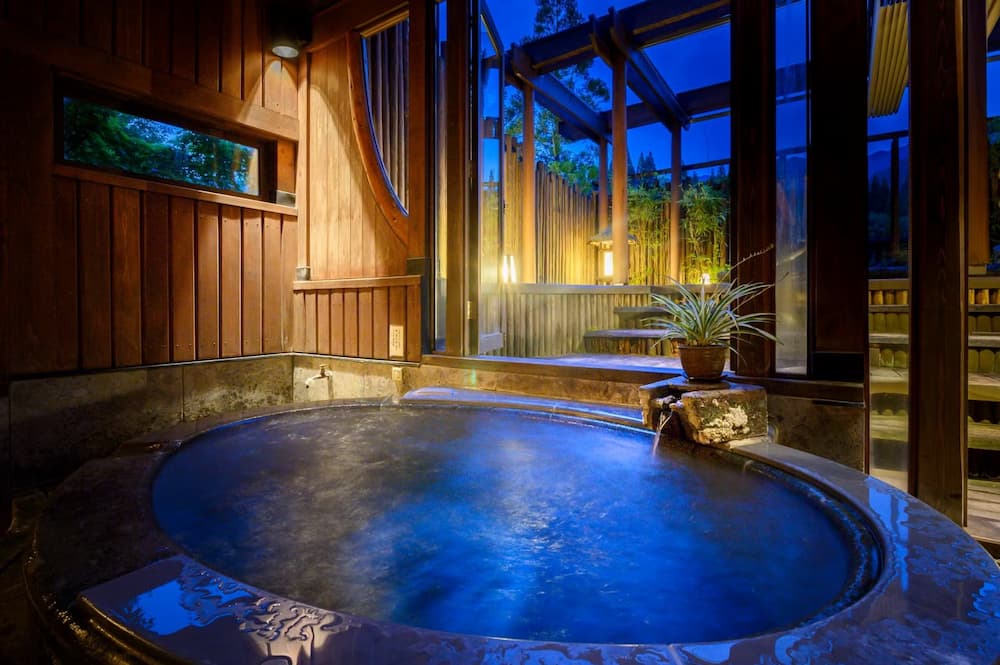 Round private onsen bath in a wooden room with large windows at Seni Onsen Iwanoyu