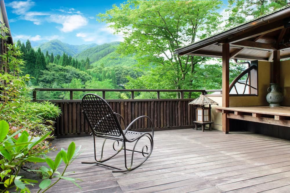 Outdoor wooden terrace with mountain view and a single chair at Seni Onsen Iwanoyu