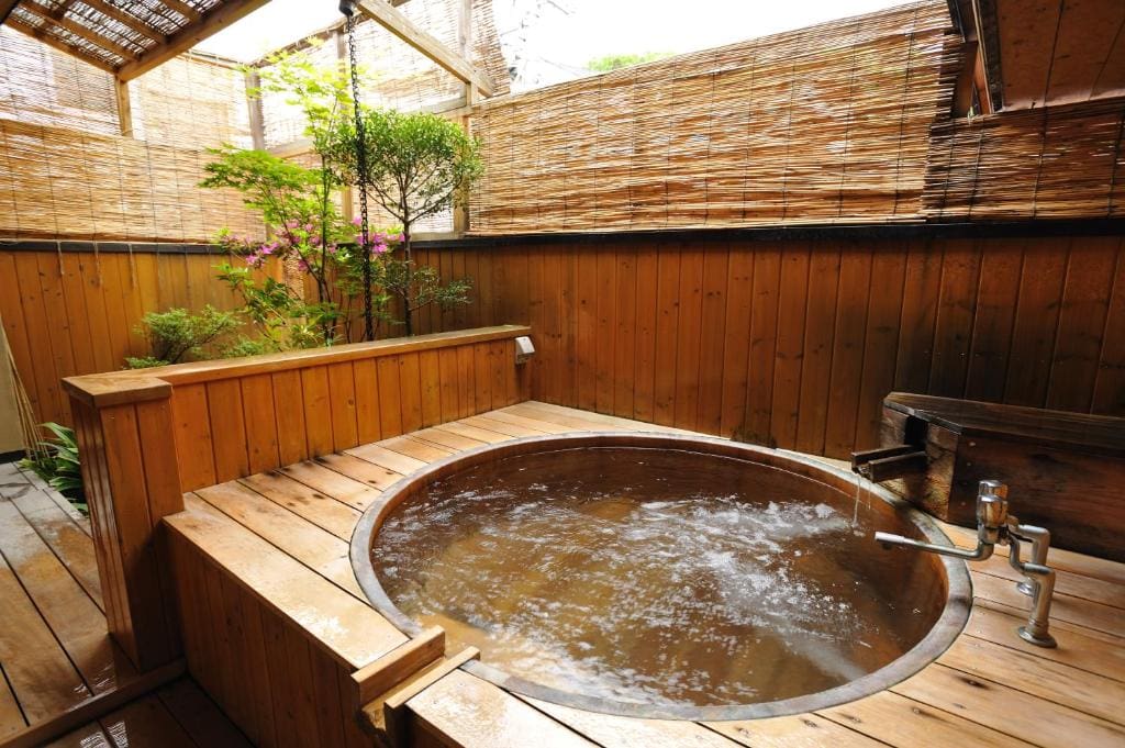 Outdoor private bath with wooden walls and bamboo screens at Shibu Onsen Kokuya