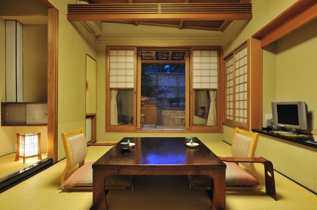 Tatami room with low table, shoji doors, and private bath visible through the window at Shibu Onsen Kokuya