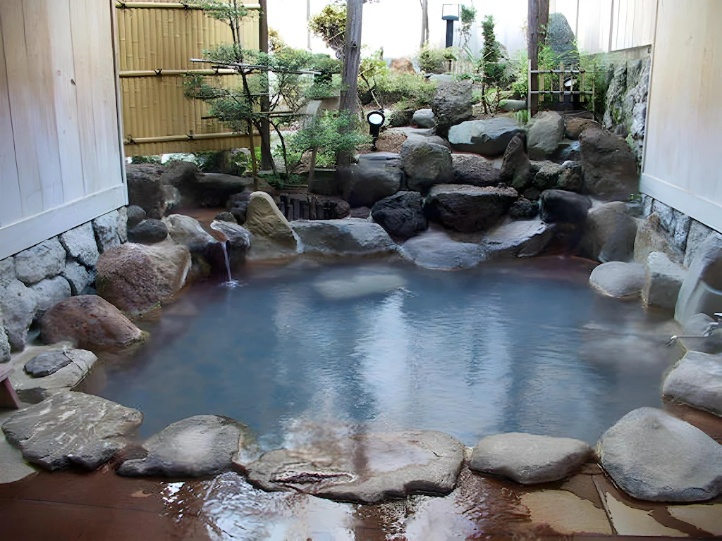 Stone-lined private outdoor bath with garden plants at Yumoto Ryokan