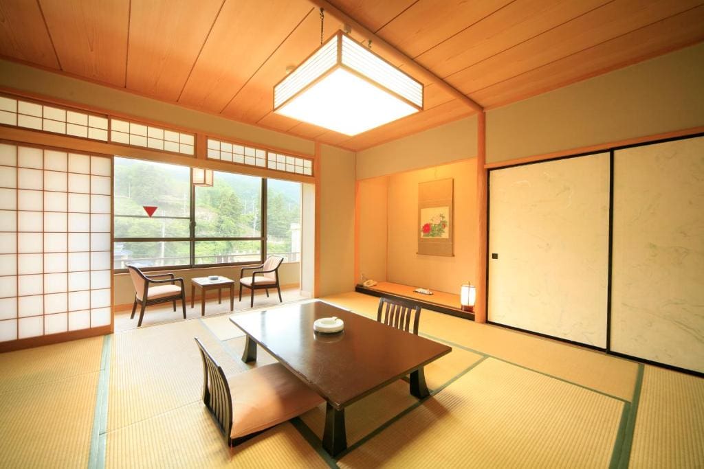 Tatami room with low table, shoji screens, and seating area by the window at Wafu-no-Yado Masuya