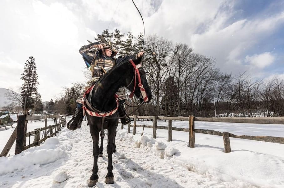 Samurai on a horse in the snow shooting an arrow to show yabusame, horseback archery