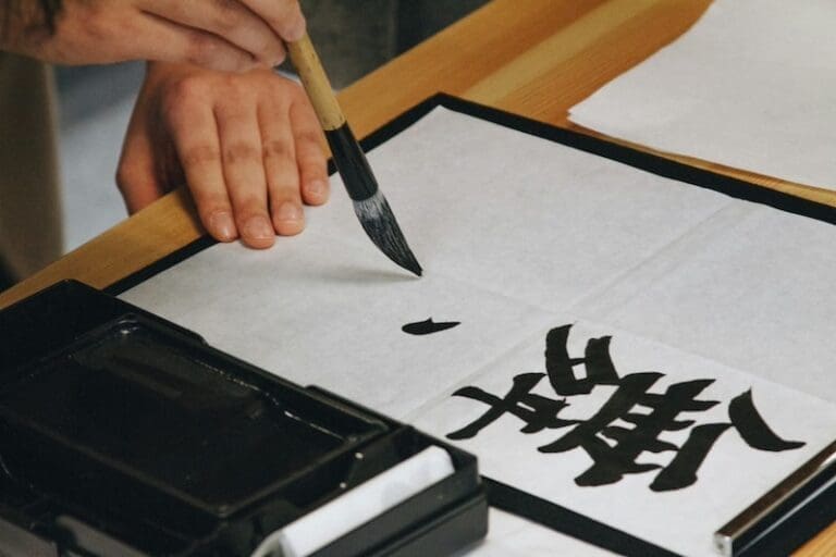 hands holding a brush doing Japanese calligraphy