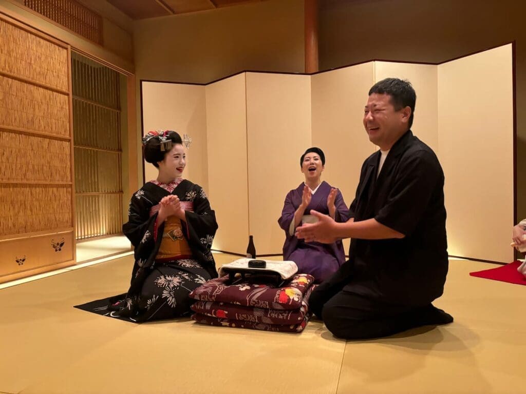 A geisha and a customer playing traditional games at a geisha dinner in Kyoto