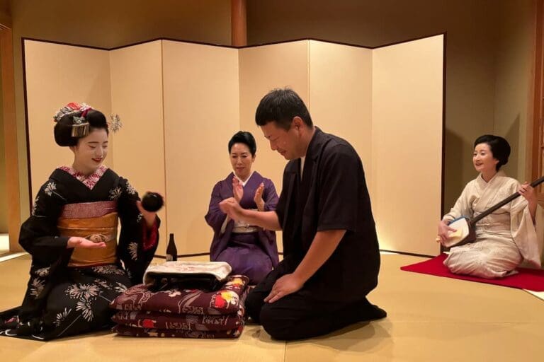 A geisha and a customer playing traditional games at a geisha dinner in Kyoto