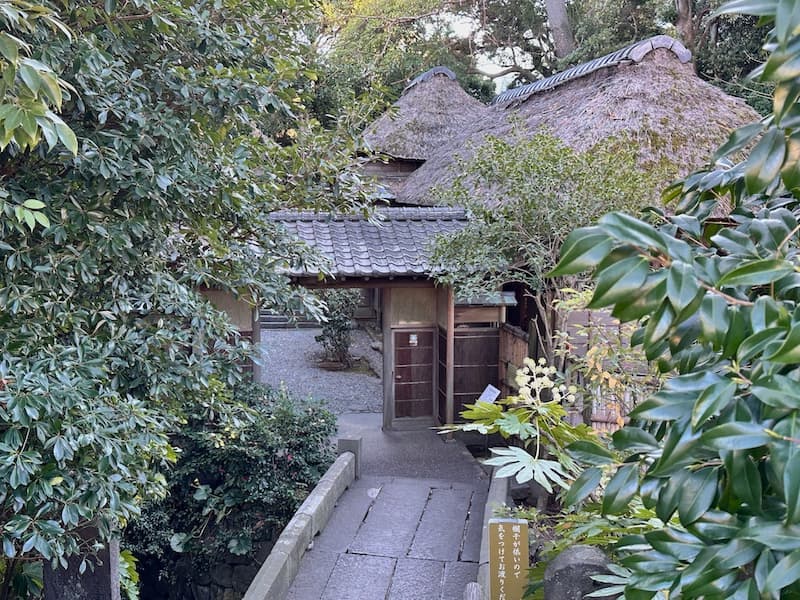 Entrance to Shigitatsuan, a historic haiku dojo with a thatched roof surrounded by greenery in Oiso.