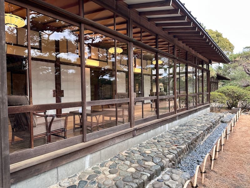 Exterior view of the Meiji Memorial Garden house with a wooden facade and large windows overlooking the garden in Oiso.