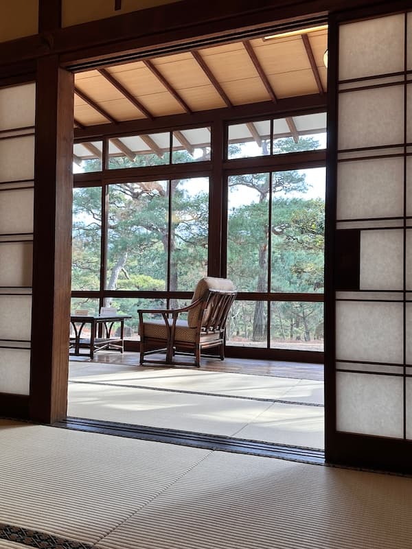 Interior of a traditional house at the Meiji Memorial Oiso Garden, showing a tatami room with sliding shoji doors and a view of the garden.
