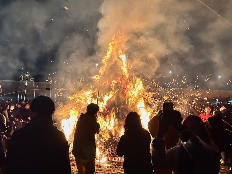 Large bonfire during the Sagicho Festival in Oiso, surrounded by people watching.