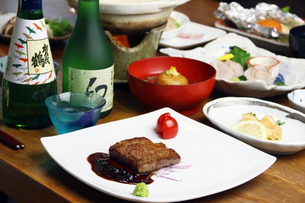 Japanese dinner set at Ryoso Kawaguchi with grilled beef, assorted sashimi, soup, and bottles of sake.