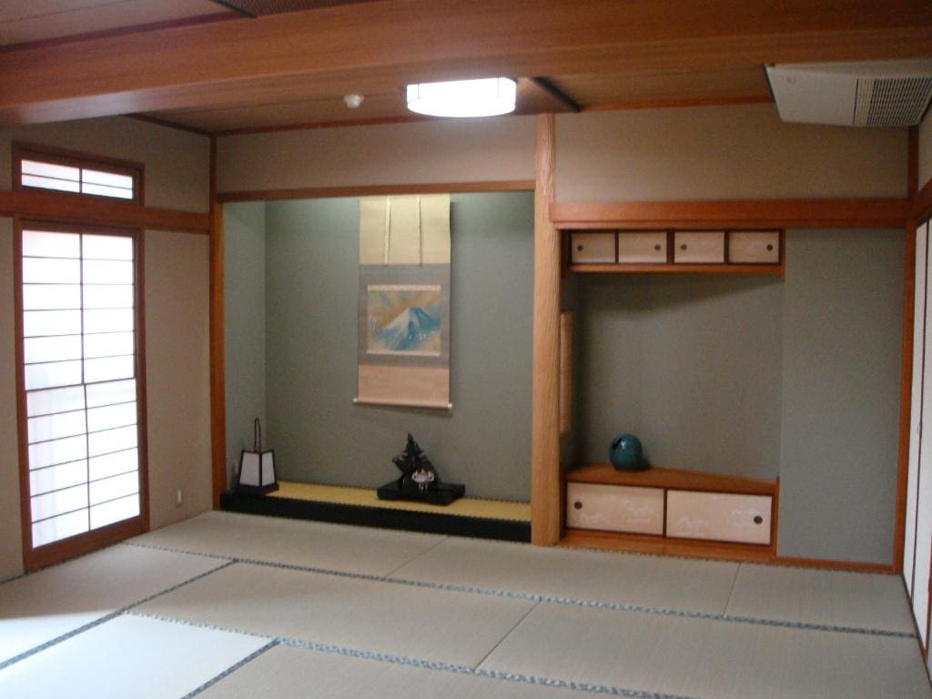 Minimalist Japanese-style room at Yamaichi Bekkan with tatami flooring, hanging scroll, and low display shelf.