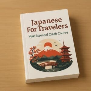 A paperback book titled “Japanese For Travelers: Your Essential Crash Course” resting on a wooden desk. This Japanese language guide is designed for travelers visiting Japan, covering essential phrases, kanji, vocabulary, and basic grammar for beginners.