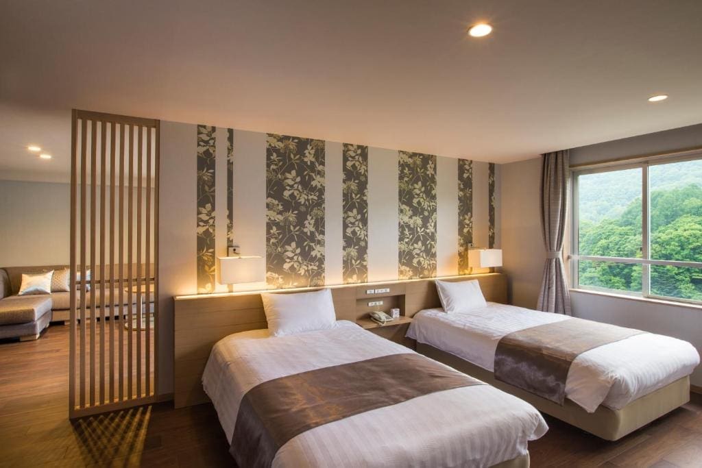 Guest room at Midorinokaze Resort Kitayuzawa with two single beds and a window overlooking green forest