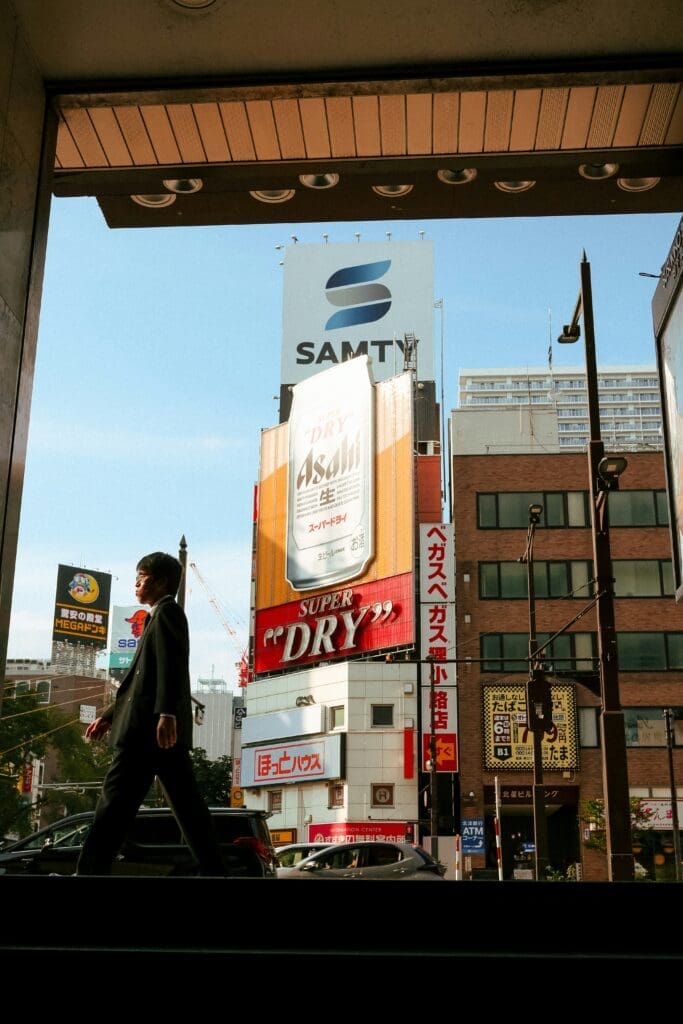 Commuter in suit walking past Asahi Super Dry billboard outside Sapporo Hokkaido metro station