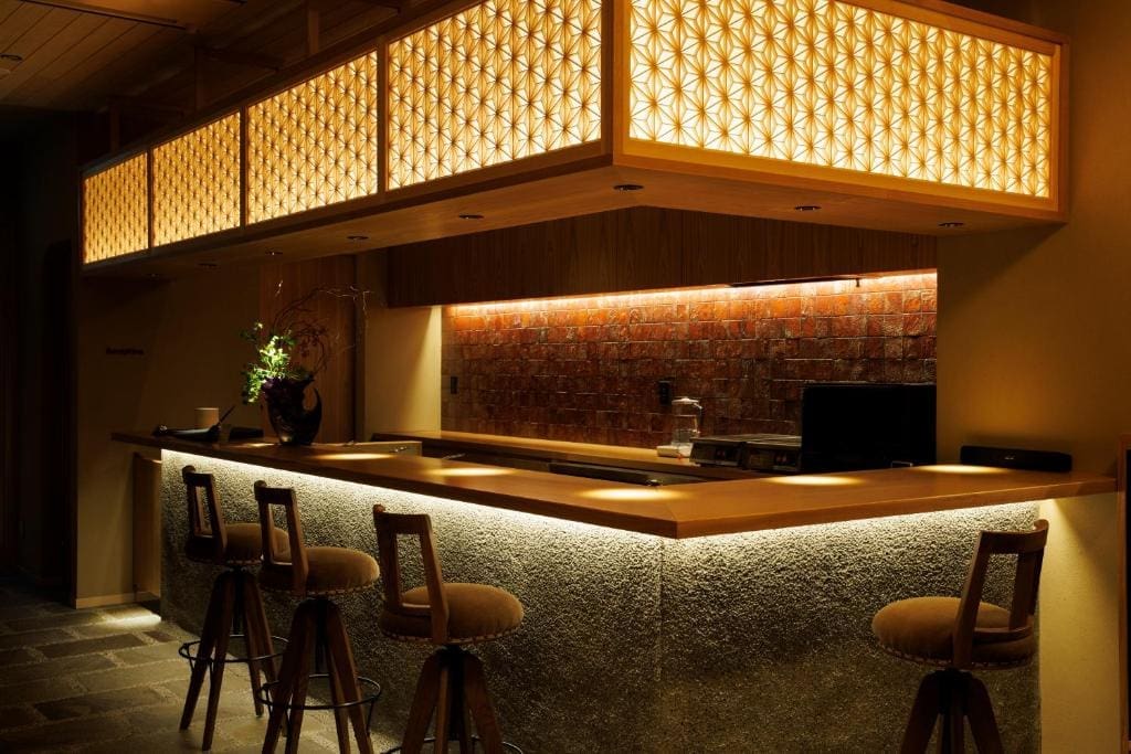 Hotel Kanazawa Zoushi wooden bar counter with stools and illuminated geometric lanterns in Kanazawa
