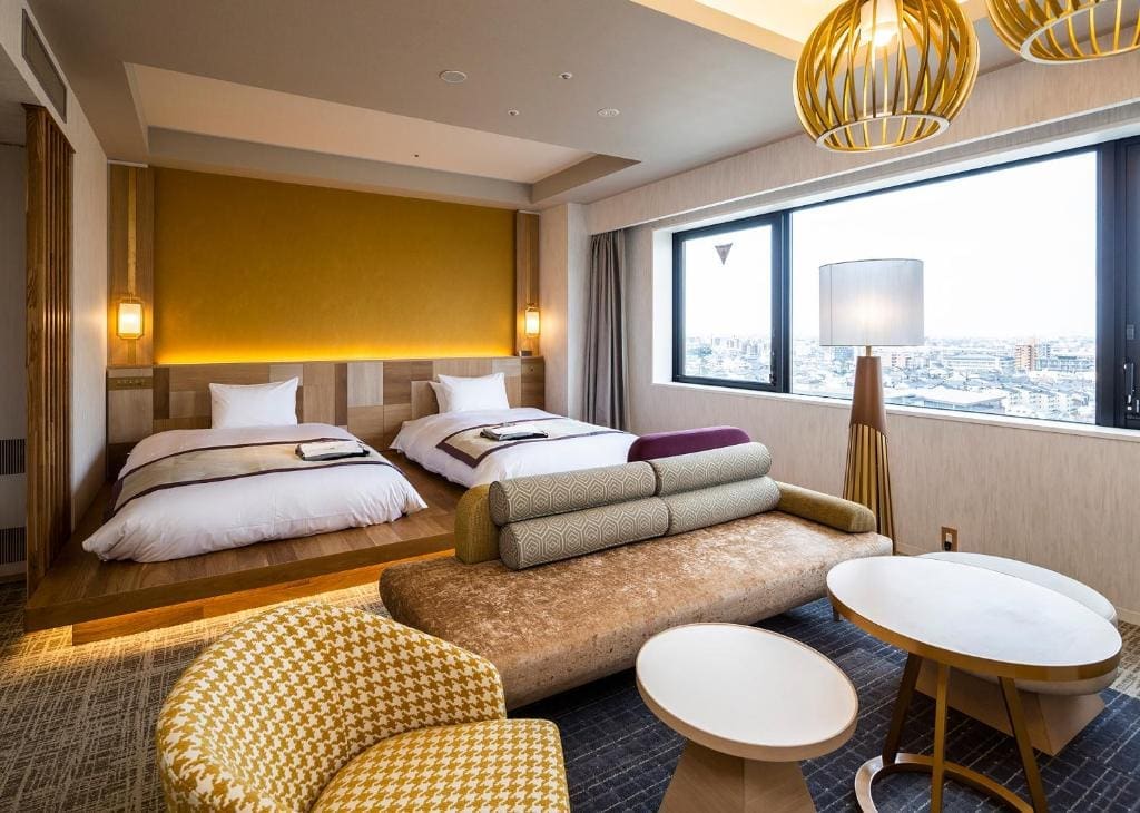 Twin beds and seating area in Hotel Intergate Kanazawa room overlooking city skyline