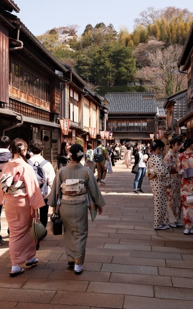 People in kimonos walking along wooden teahouse street in Kanazawa Higashi Chaya District