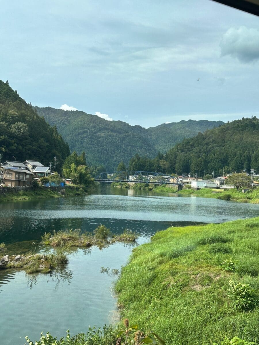 Japanese mountain village by river with steel truss bridge