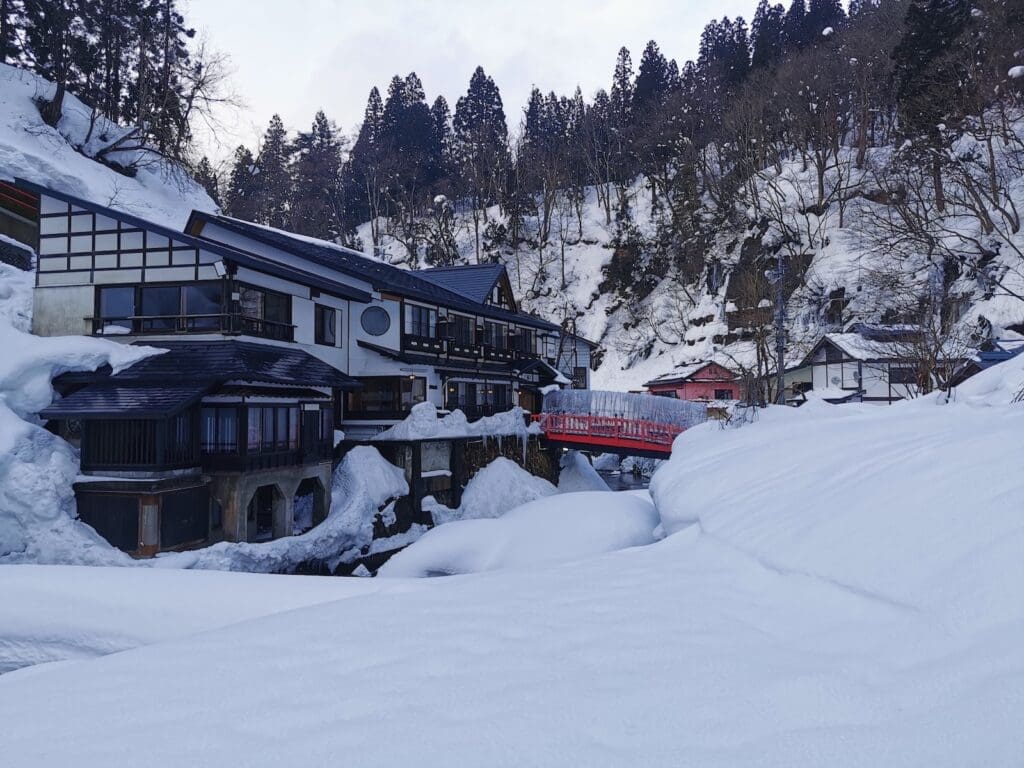 Snow-covered ryokan and red bridge at Ginzan Onsen, Yamagata