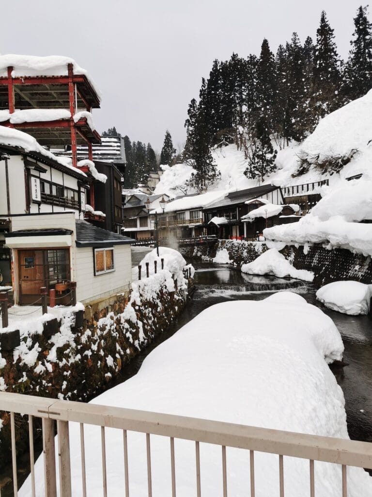 Snow-covered riverside buildings at Ginzan Onsen in Yamagata, Japan, viewed from a bridge