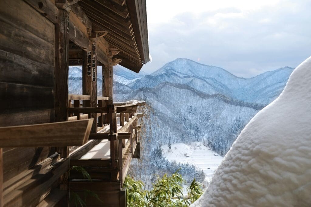 Wooden temple balcony at Yamadera overlooking snowy mountains in Yamamoto, Miyagi, Japan