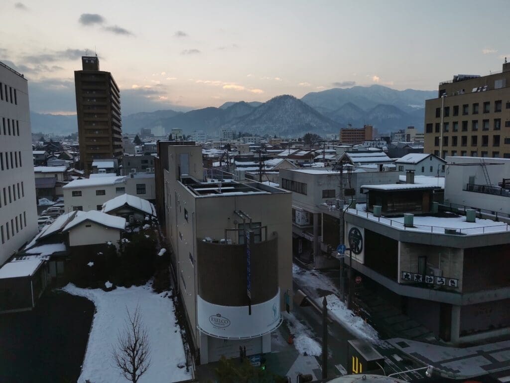 Snow-covered rooftops and distant mountains at dusk in Yamagata, viewed from Yamagata Grand Hotel